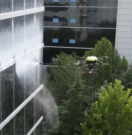 Pulizia di vetrate e rivestimenti di facciata con drone Drone che lava una facciata a vetri con un getto d’acqua